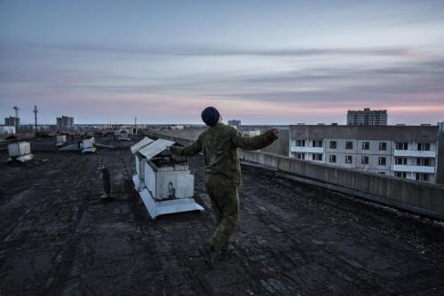 Uno stalker mentre balla al tramonto sul tetto di un edificio della città fantasma di Pripyat.